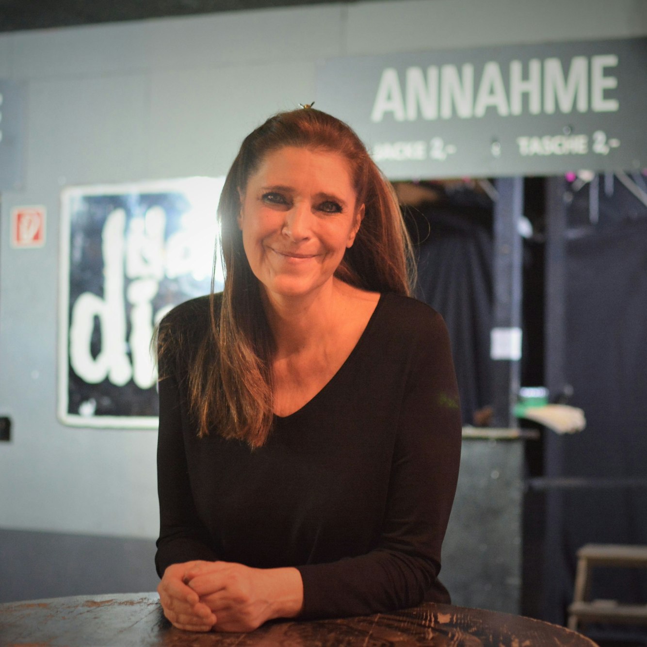 Claudia Wecker am Tisch in ihrem Club, im Hintergrund die Garderobe.