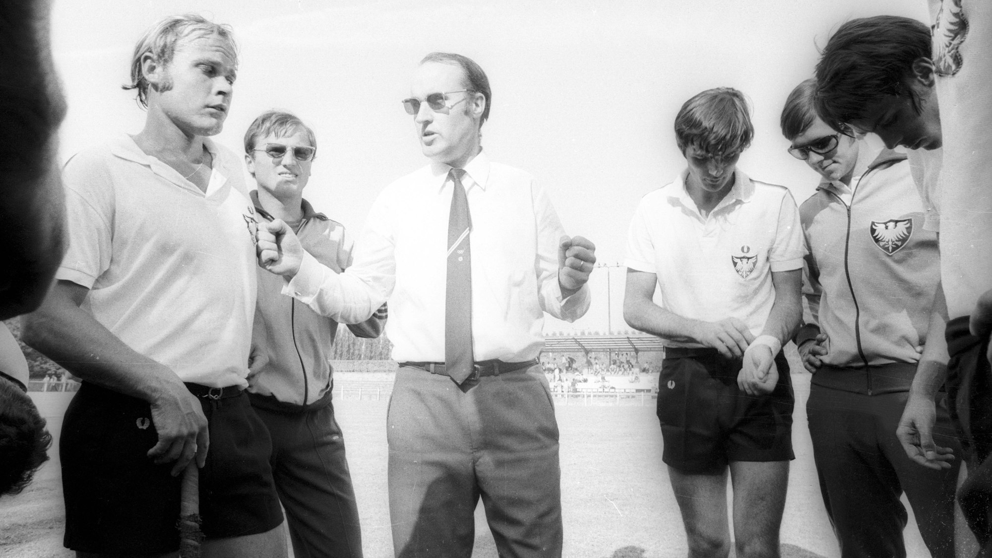Bundestrainer Werner Delmes gibt bei der Hockey-Europameisterschaft in Belgien im Jahr 1970 Anweisungen an seine Spieler. Der Kölner Trainer trägt Hemd und Krawatte.