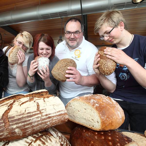 Der Kürtener Bäckermeister Mario Fritzen und sein Team halten Brotlaibe in der Hand.