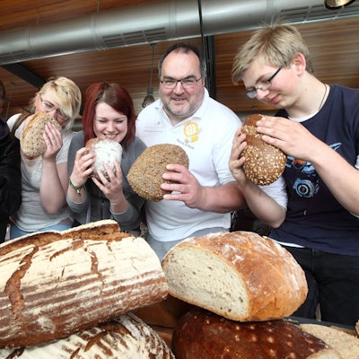Der Kürtener Bäckermeister Mario Fritzen und sein Team halten Brotlaibe in der Hand.