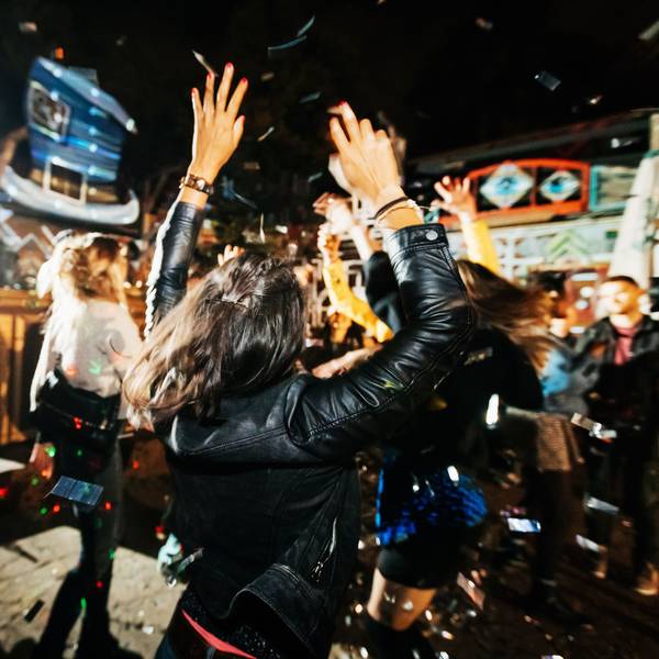 Eine Frau mit schwarzer Lederjacke steht auf einer Tanzfläche in einem Club und tanzt.