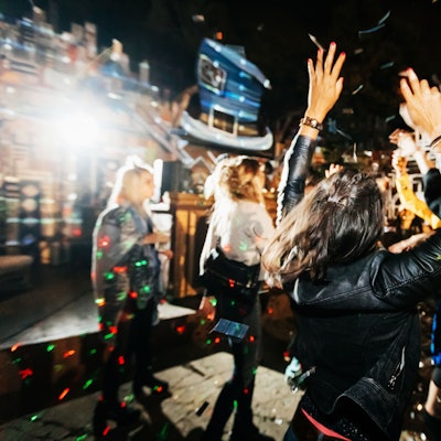Eine Frau mit schwarzer Lederjacke steht auf einer Tanzfläche in einem Club und tanzt.