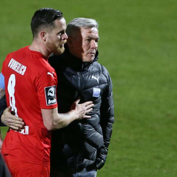 Ein Fußballtrainer nimmt seinen Kapitän nach Spielschluss in den Arm.