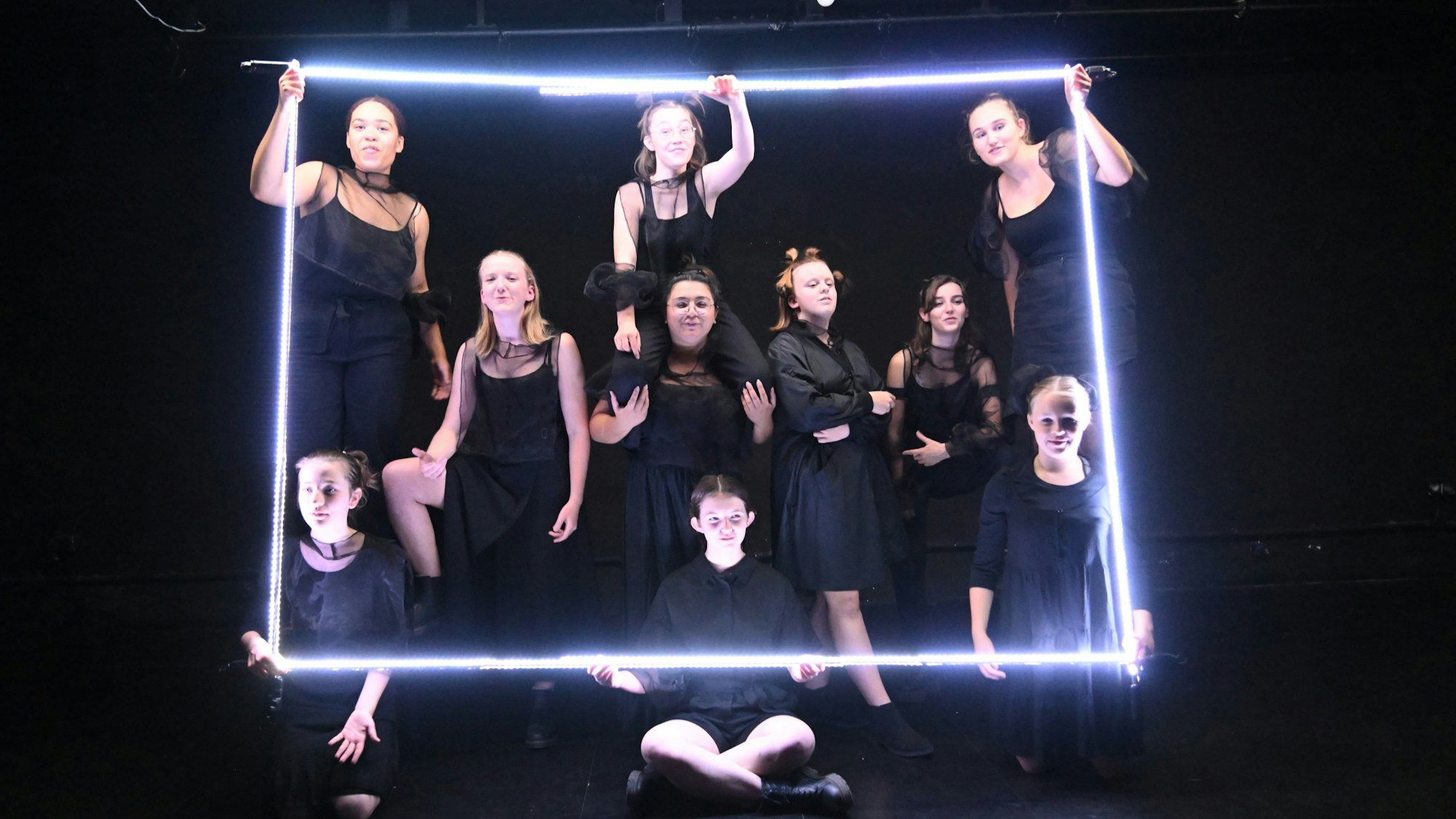 Mitgelider des Jungen Ensemble des Theas-Theaters bei der Produktion „Lichterfangen“, ganz in Schwarz mit Lichtröhren zu einem Quadrat geformt.