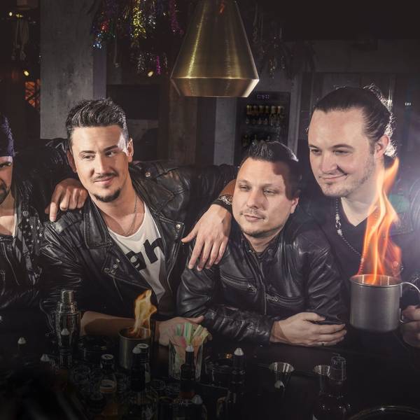 Fünf Musiker stehen an einer Theke und haben brennende Drinks vor sich stehen.