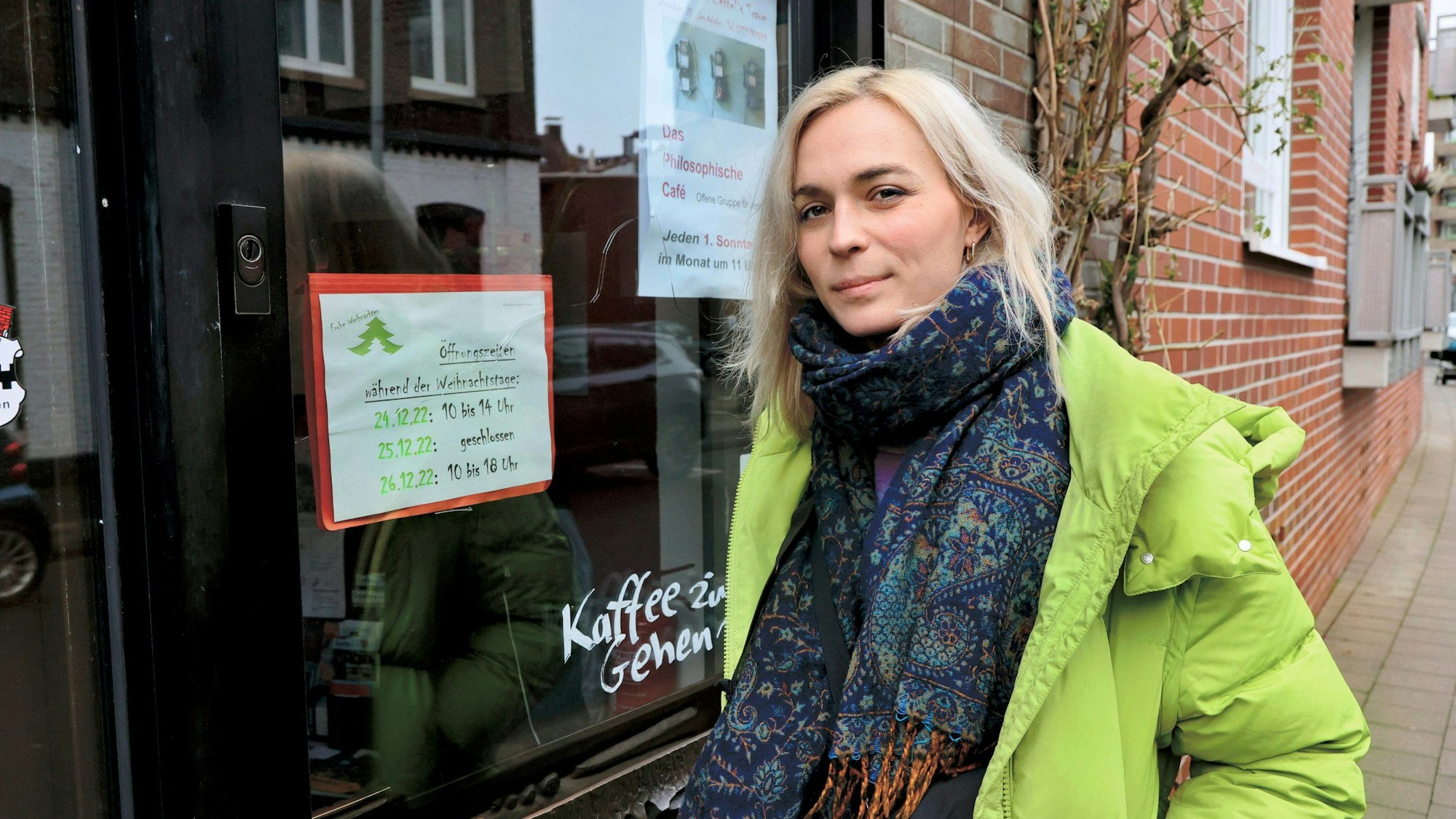 Nyke Slawik steht vor einem Leverkusener Café auf dem Bürgersteig und schaut in die Kamera.