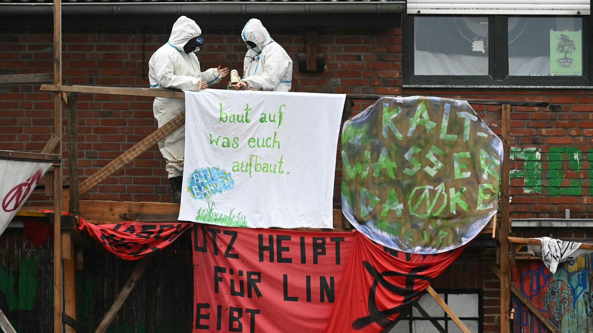 Aktivisten hängen ein Plakat auf, um gegen die Räumung von Lützerath zu protestieren.