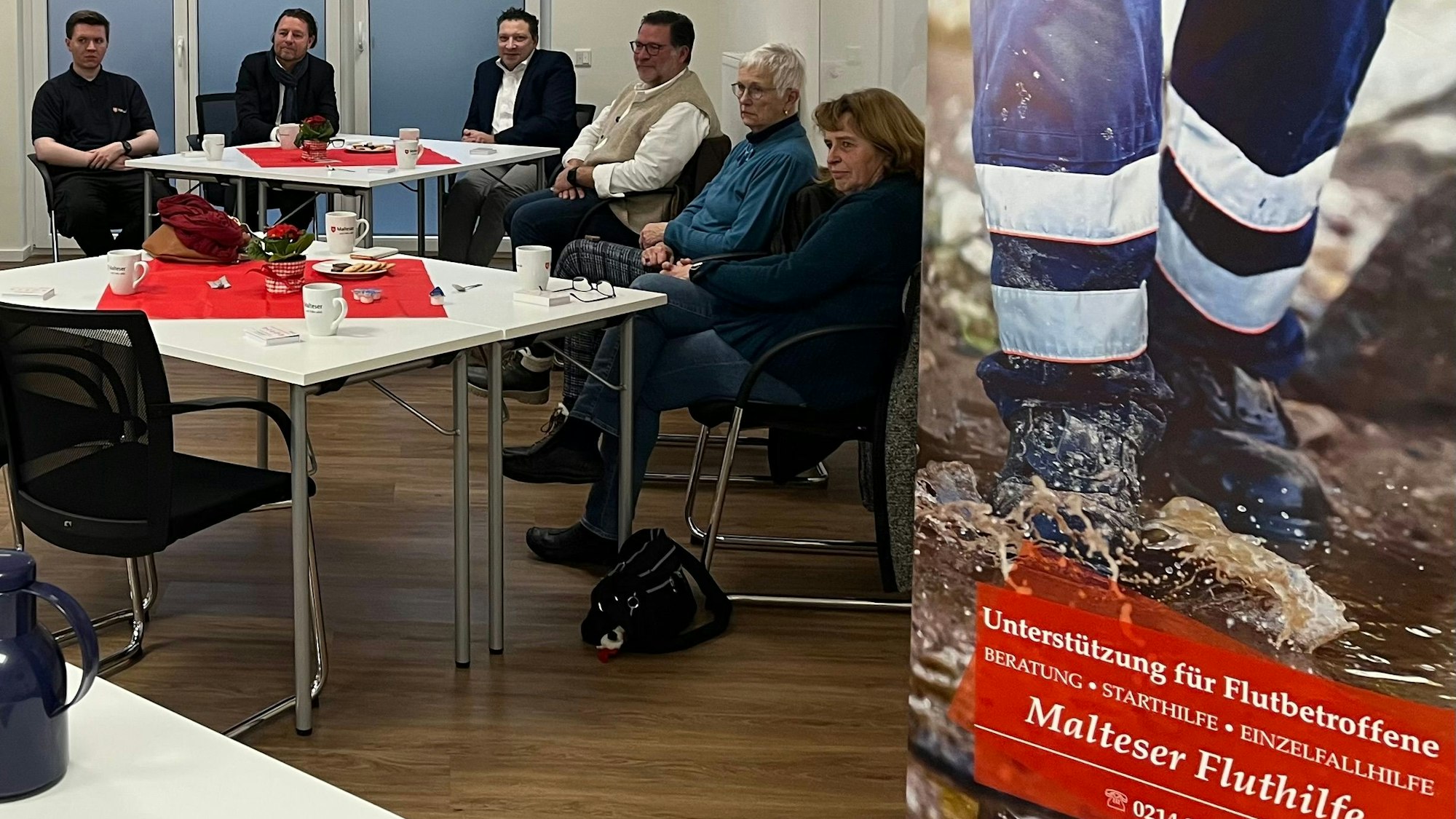 Menschen sitzen in einem Raum an Kaffeetischen