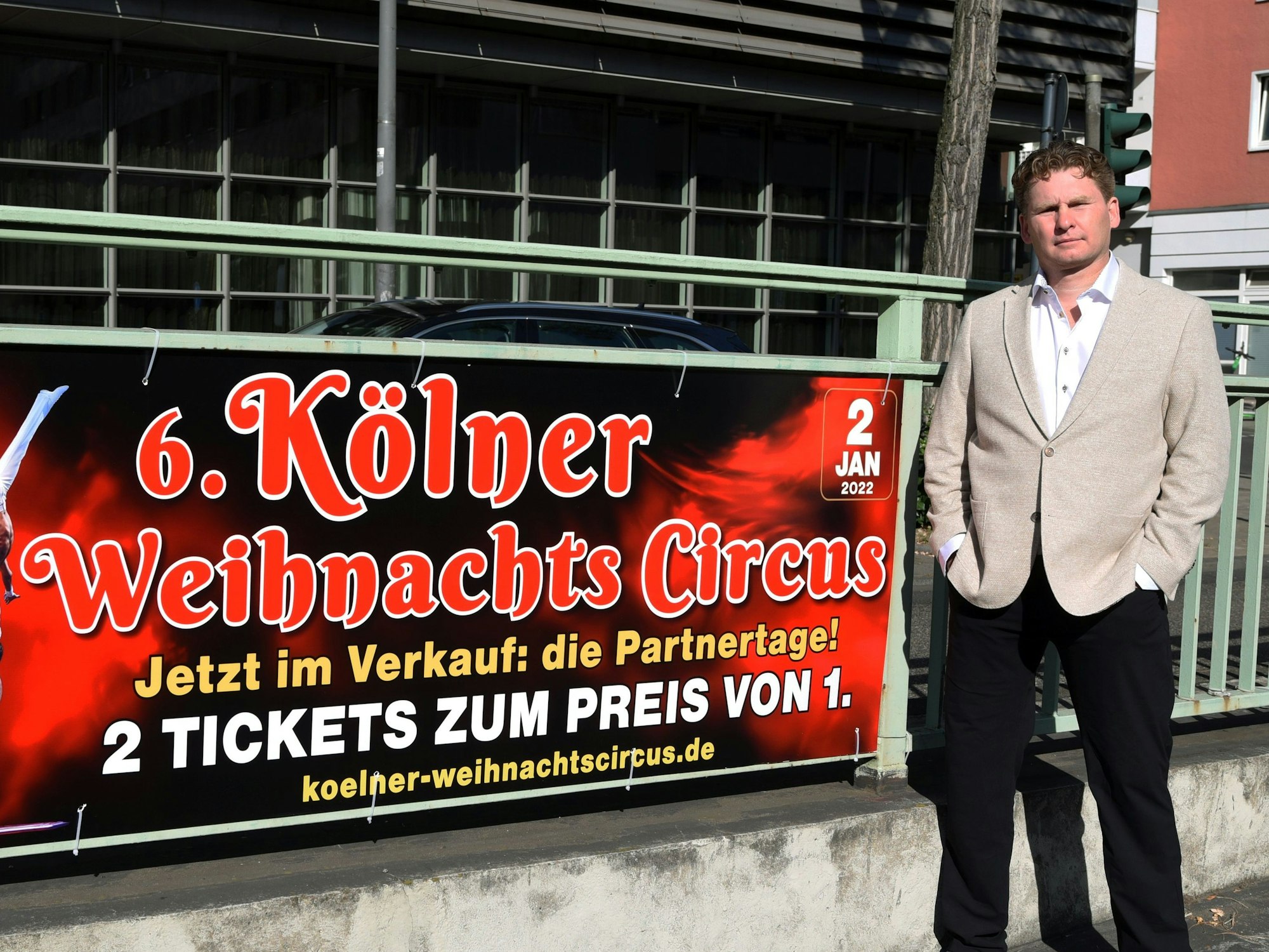 Zirkusdirektor Ilja Smitt steht neben dem Werbeplakat für den Weihnachtscircus.