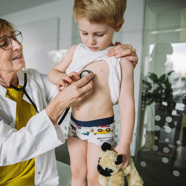 Eine Kinderärztin untersucht einen kleinen Jungen mit dem Stethoskop.