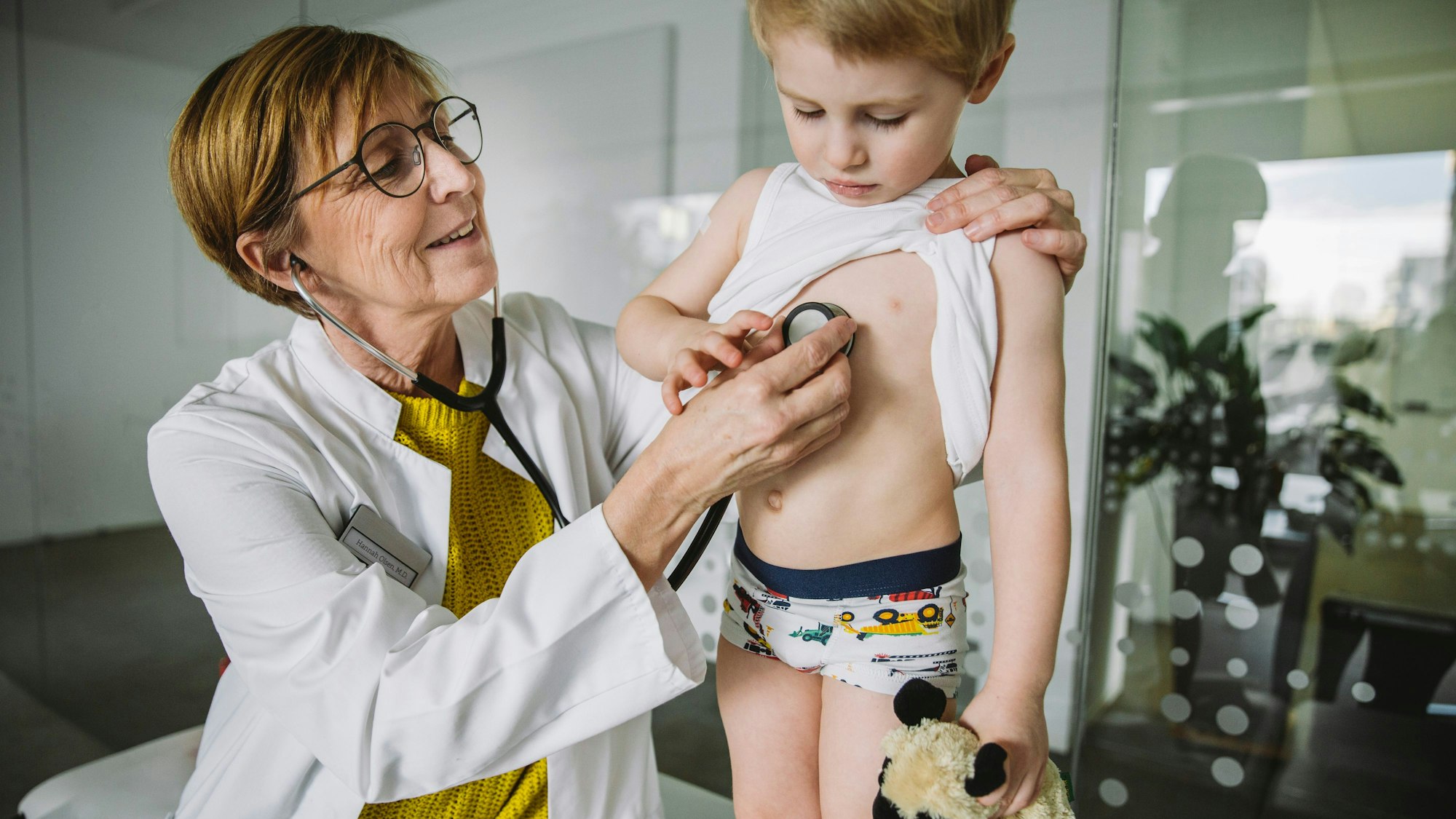 Eine Kinderärztin untersucht einen kleinen Jungen mit dem Stethoskop.