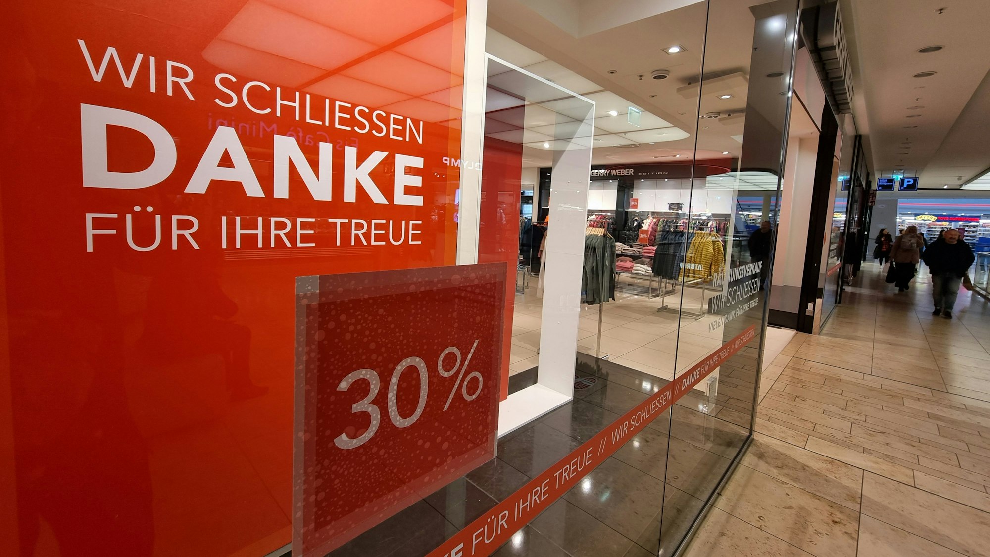 Blick auf das Schaufenster der Filiale von Gerry Weber in der Rathaus-Galerie Leverkusen. Im Fenster hängt ein rot-weißes Schild, auf dem steht: „Wir schließen. Danke für Ihre Treue.“