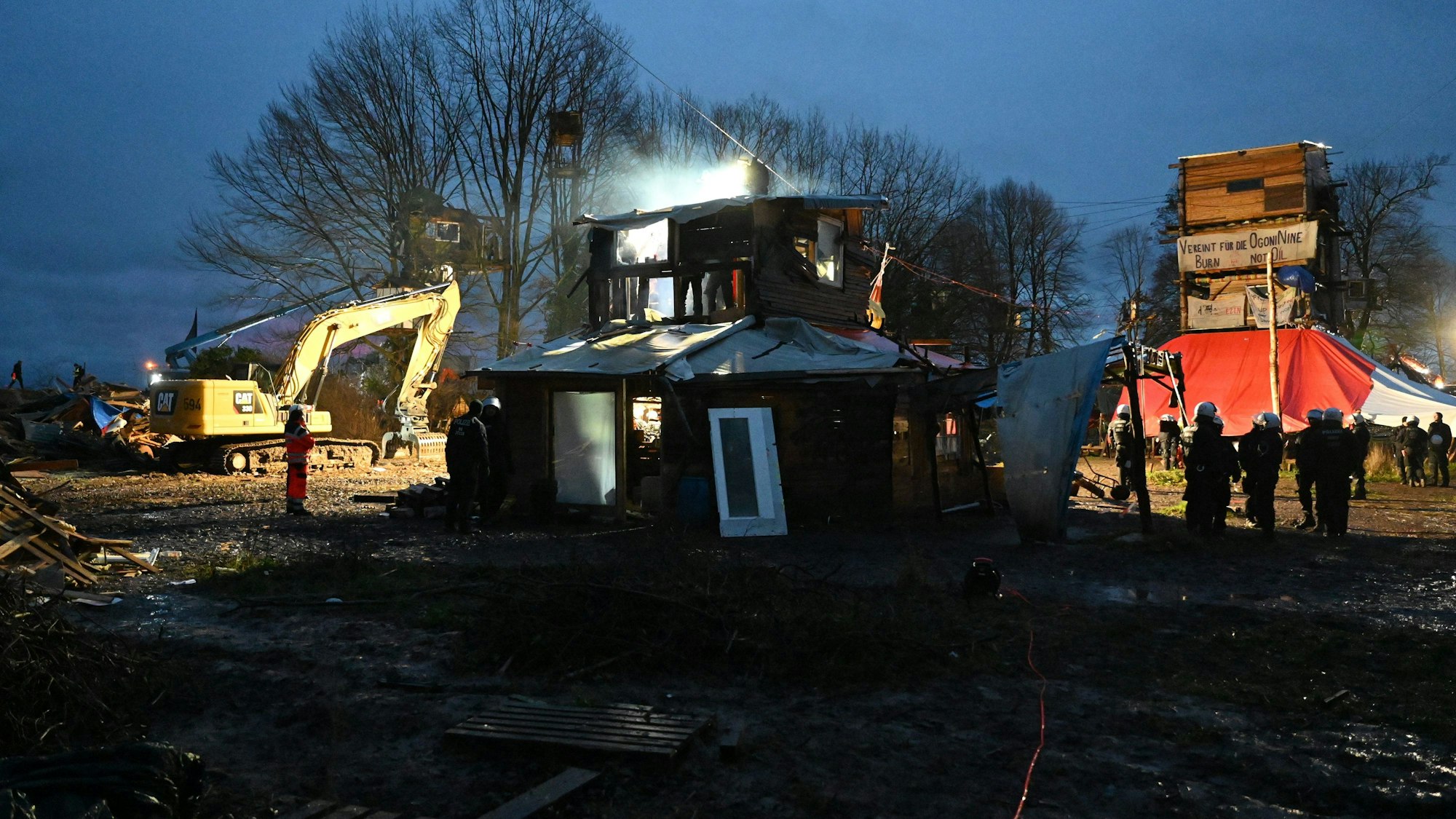 Polizisten stehen bei Räumung im von Klimaaktivisten besetzten Braunkohleort Lützerath vor einer Holzhütte. Unter den Hütten und Barrikaden wurden Tunnel gefunden, die Aktivisten sprachen zuvor von einem Tunnelsystem.