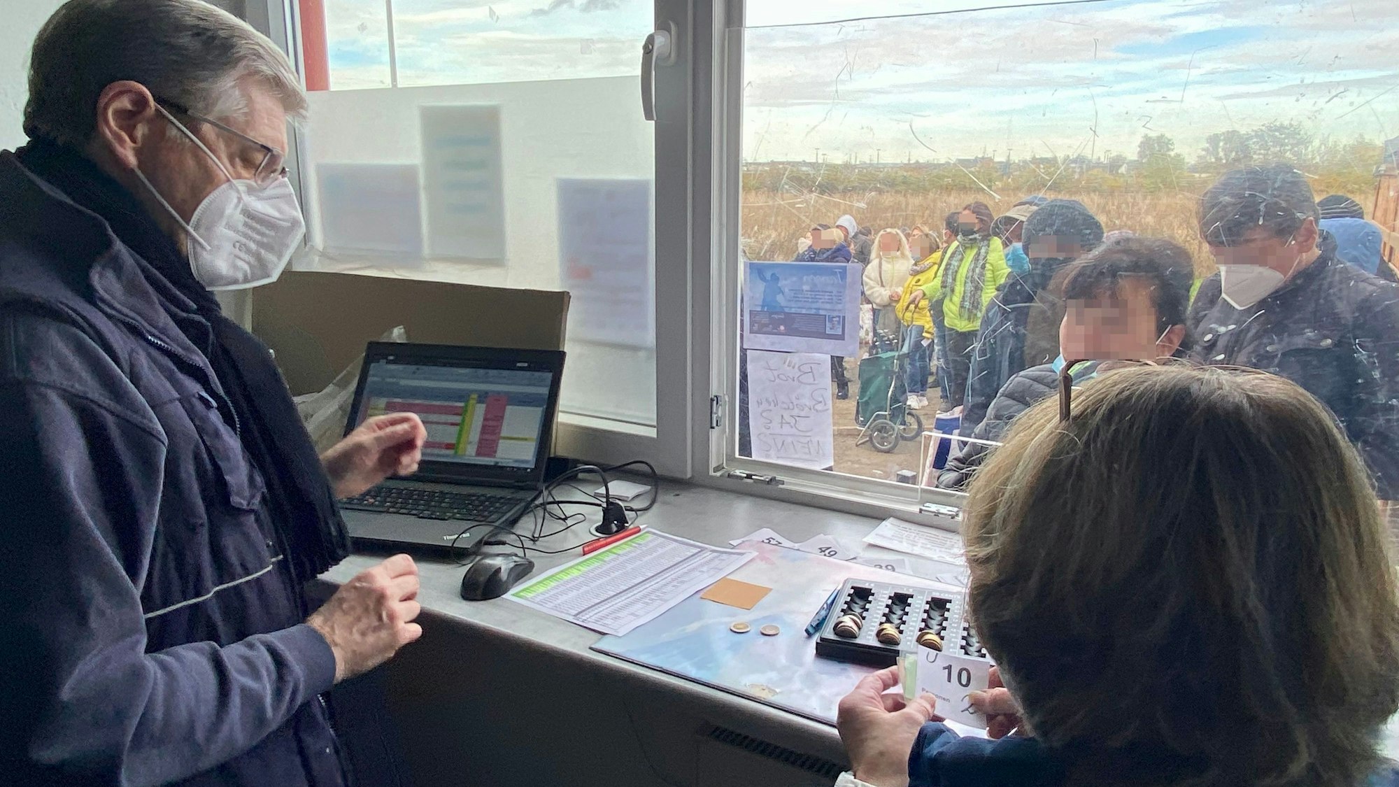 Vor dem Schalter der Tafel warten Kunden in einer Schlange, um ein Los für die Reihenfolge zu ziehen und ihren Beitrag zu zahlen.