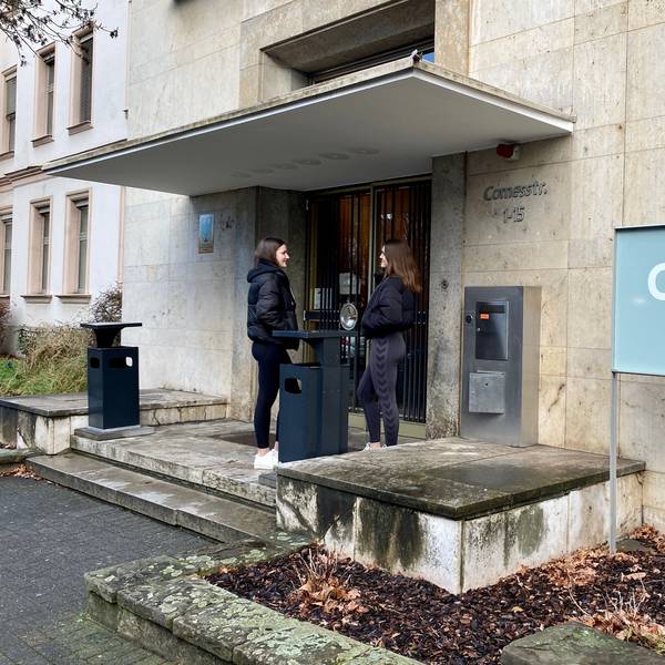Zwei Studierende stehen vor dem Eingang der Cologne Business School.