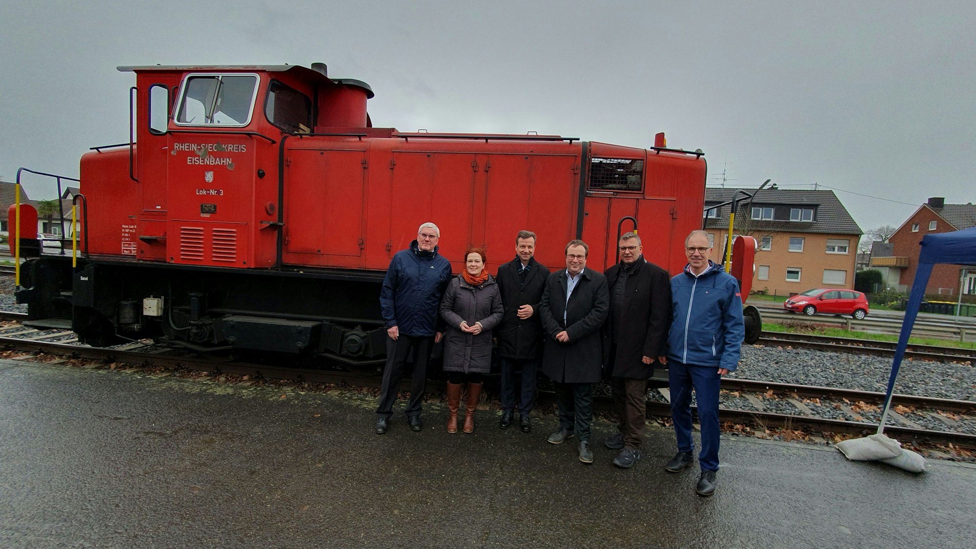 Vor einem roten Straßenbahn-Wagon stehen mehrere Personen, unter anderem NRW-Verkehrsminister Oliver Krischer.