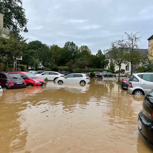 Autos stehen nach dem Hochwasser in einem See aus braunem Wasser..
