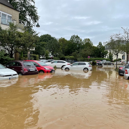 Autos stehen nach dem Hochwasser in einem See aus braunem Wasser..