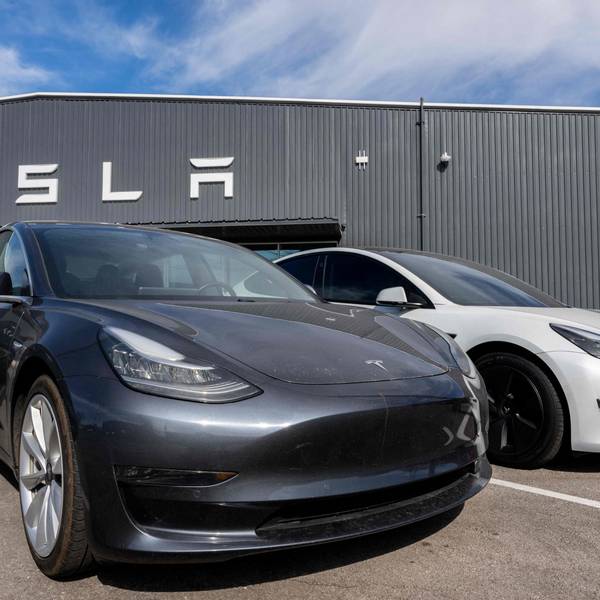 Autos von Tesla stehen vor einem Autohaus von Tesla.