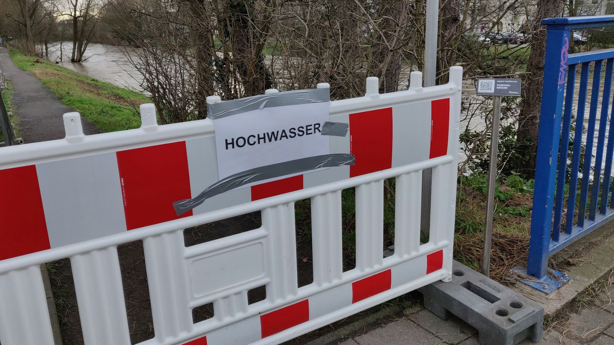 Ein Baugitter mit der Aufschrift "Hochwasser" steht am Wupperuferweg.