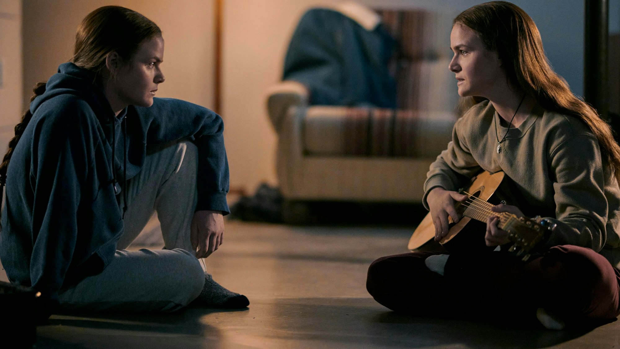 Die Zwillinge Tegan and Sara sitzen auf dem Boden mit einer Gitarre