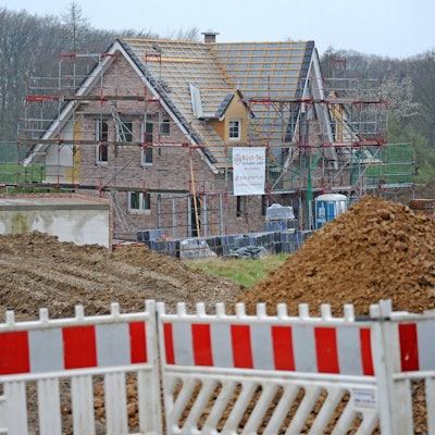 Foto einer Baustelle eines Einfamilienhauses, das noch keine Dachabdeckung hat und noch eingerüstet ist.