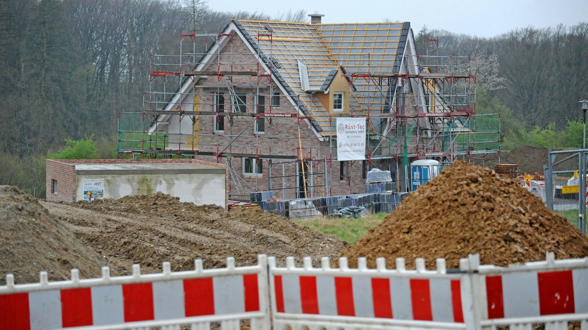 Foto einer Baustelle eines Einfamilienhauses, das noch keine Dachabdeckung hat und noch eingerüstet ist.