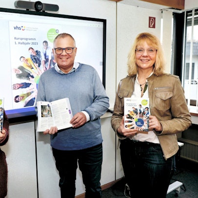 Marjanne Meeuwsen, Frank Steffes, Annette Langen (v.l.). stehen nebeneinander und halten VHS-Broschüren in die Kamera.
