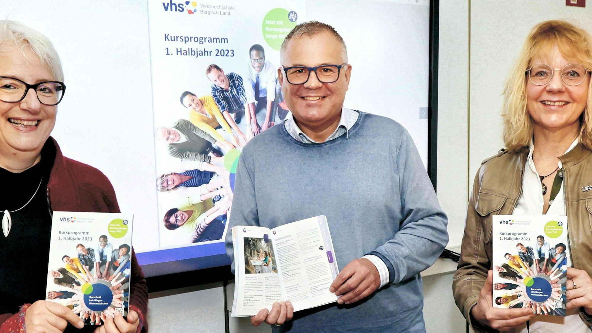 Marjanne Meeuwsen, Frank Steffes, Annette Langen (v.l.). stehen nebeneinander und halten VHS-Broschüren in die Kamera.