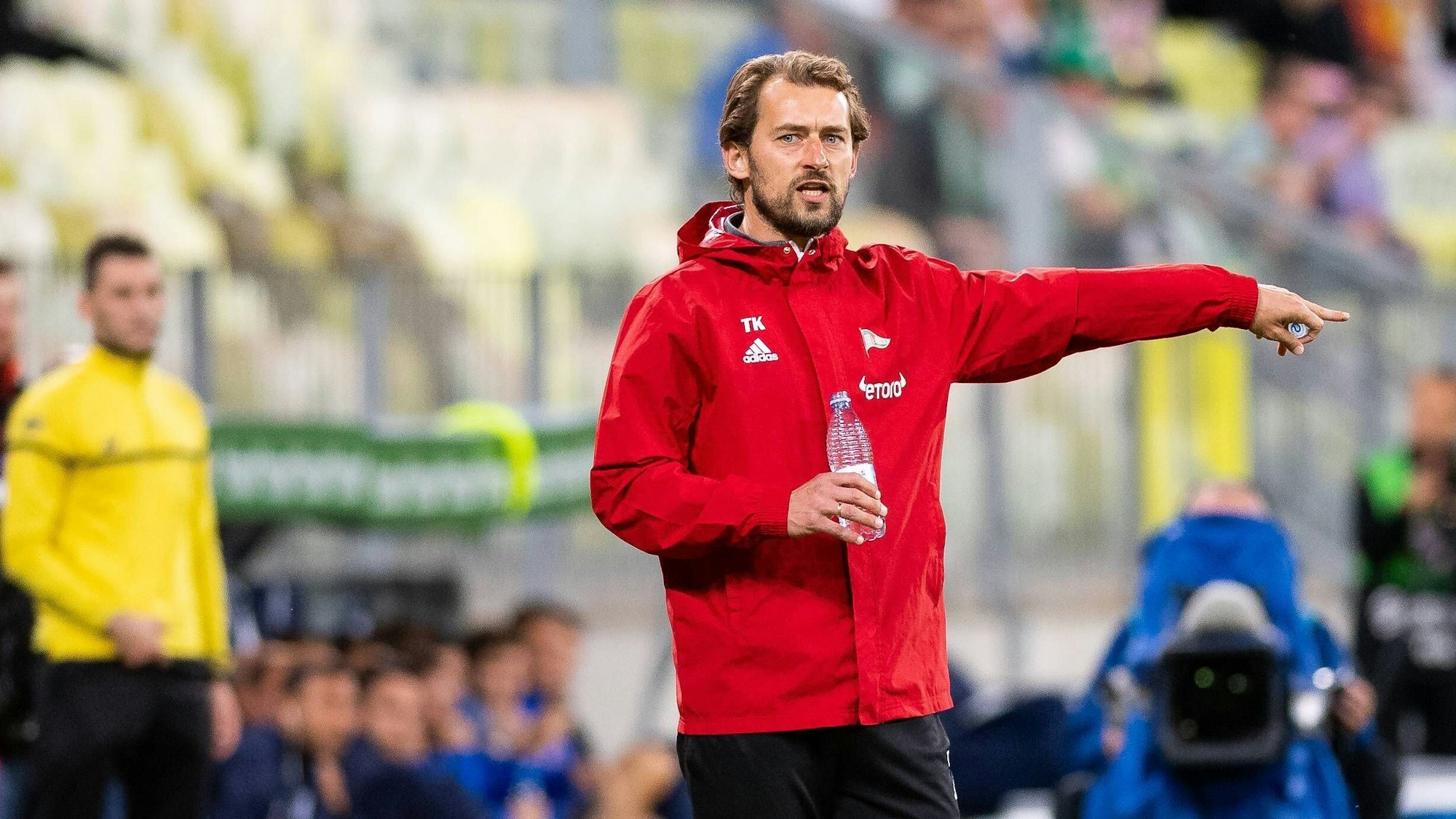 Der Gummersbacher Tomek Kaczmarek steht als Fußballtrainer am Spielfeldrand und zeigt mit dem Finger nach rechts.