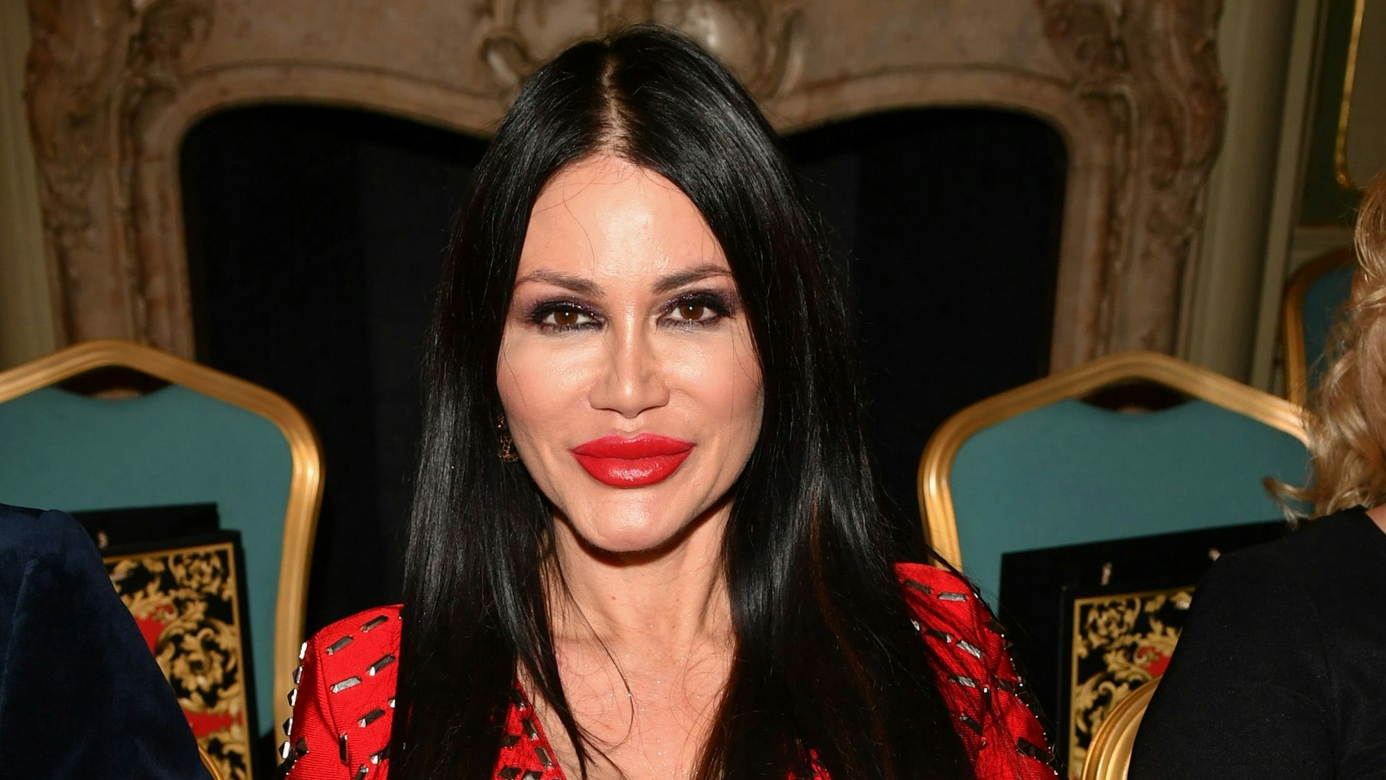 Djamila Rowe sitzt und lächert.