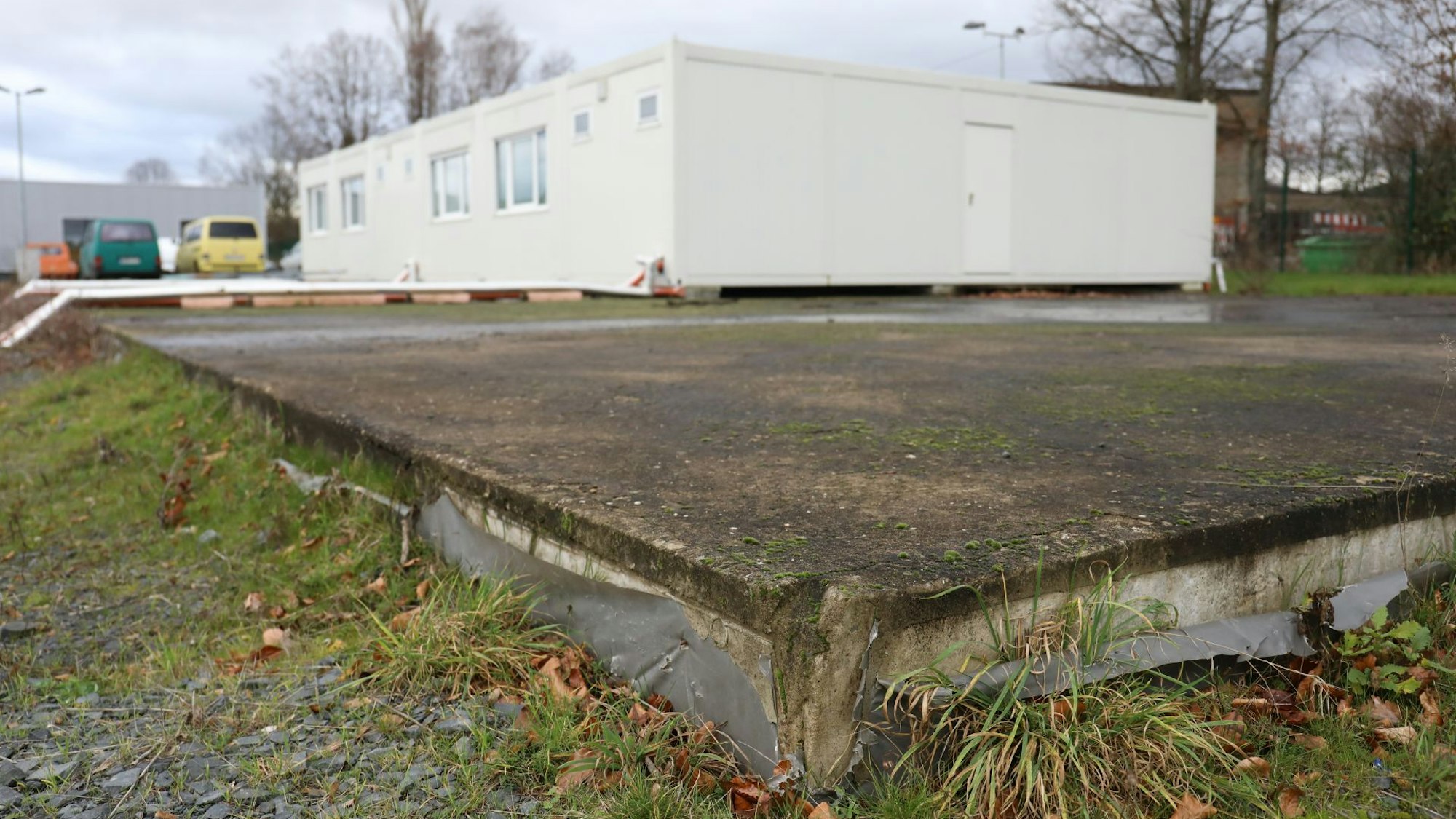 Auf einer großen Bodenplatte steht ein weißer Wohncontainer.