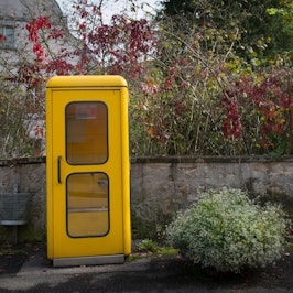 Eine gelbe Telefonzelle steht am Rande einer Straße.