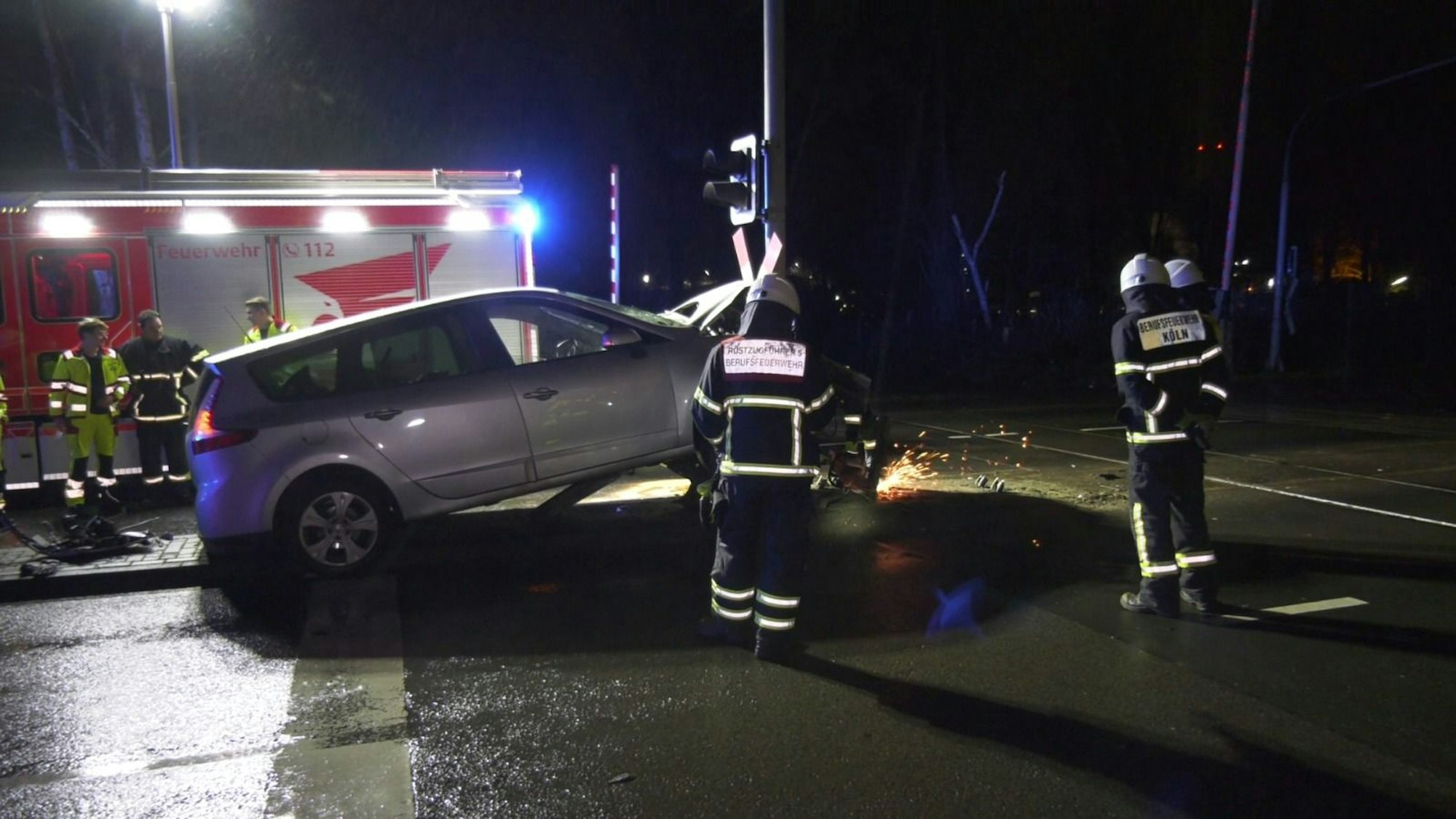 Feuerwehrleute versuchen, den vorderen Teil des beschädigten Pkws von der Ampel zu trennen.