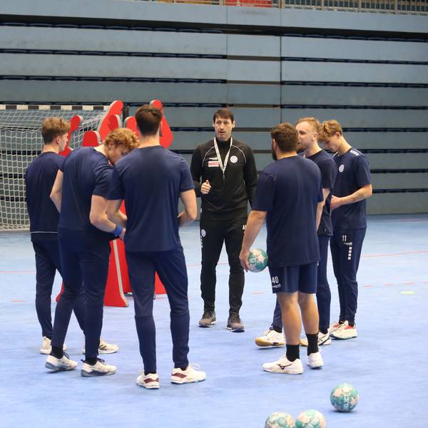 Mehrere Handballspieler des VfL Gummersbach stehen mit ihrem Co-Trainer im Kreis.