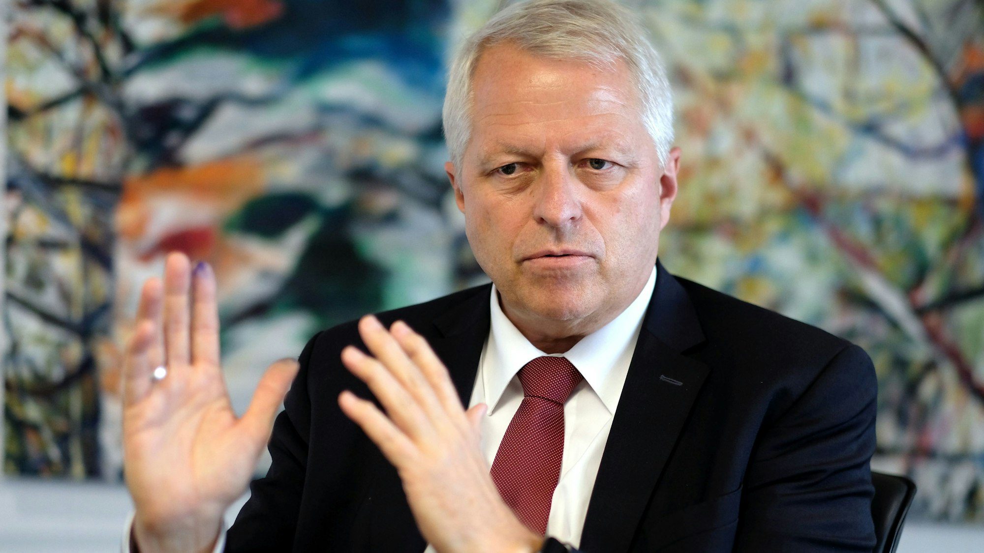 Jürgen Mathies sitzt hinter einem Schreibtisch und gestikuliert im Gespräch mit seinen Händen