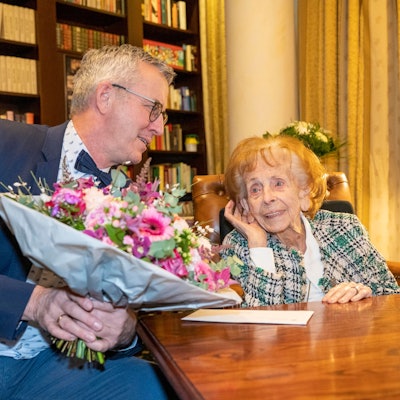 Wolter überreicht Steubesand am Tisch einen Blumenstrauß.