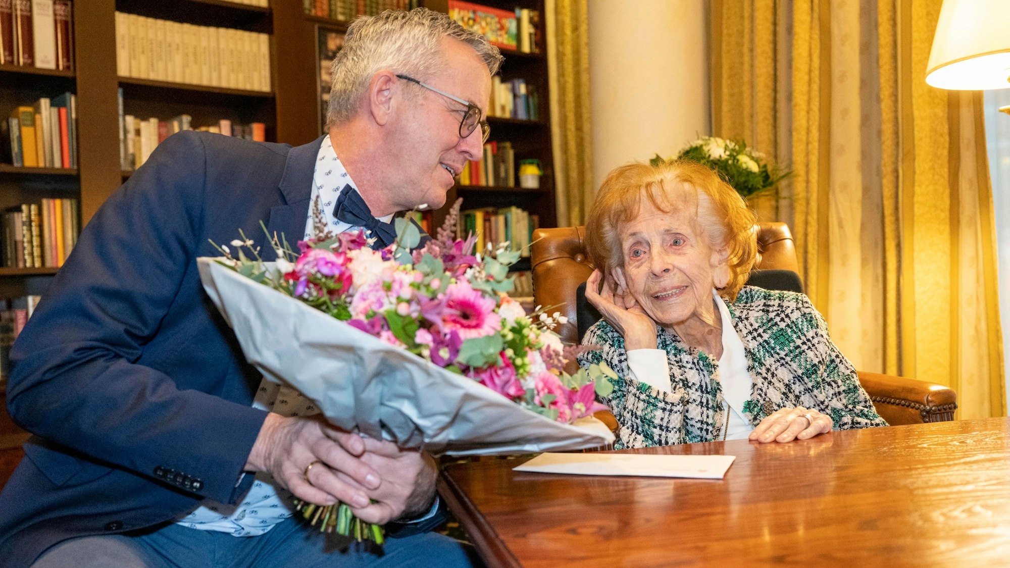 Wolter überreicht Steubesand am Tisch einen Blumenstrauß.
