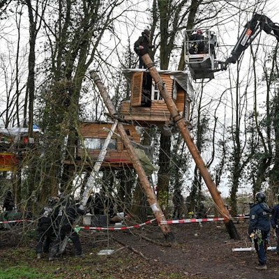 Polizisten sprechen von einer Hebebühne aus mit einem Aktivisten der am dritten Tag der Räumung im von Klimaaktivisten besetzten Braunkohleort Lützerath auf einem Baumhaus steht. Der Energiekonzern RWE will die unter Lützerath liegende Kohle abbaggern - dafür soll der Weiler auf dem Gebiet der Stadt Erkelenz am Braunkohletagebau Garzweiler II abgerissen werden.