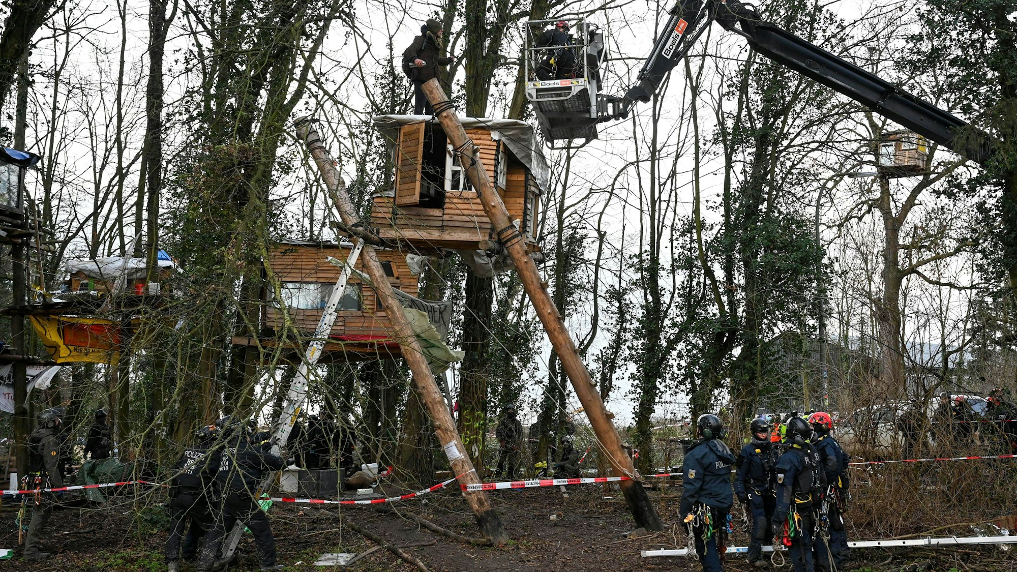 Polizisten sprechen von einer Hebebühne aus mit einem Aktivisten der am dritten Tag der Räumung im von Klimaaktivisten besetzten Braunkohleort Lützerath auf einem Baumhaus steht. Der Energiekonzern RWE will die unter Lützerath liegende Kohle abbaggern - dafür soll der Weiler auf dem Gebiet der Stadt Erkelenz am Braunkohletagebau Garzweiler II abgerissen werden.