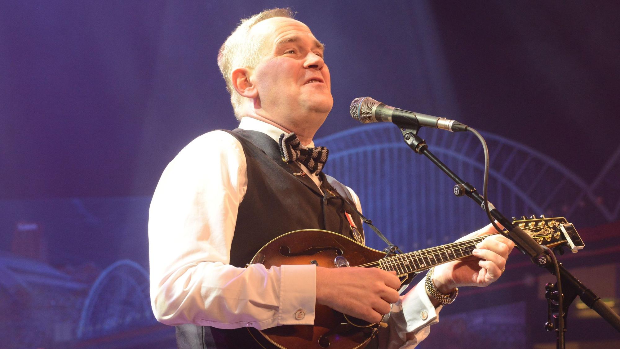 Weber mit Gitarre vor dem Mikro.