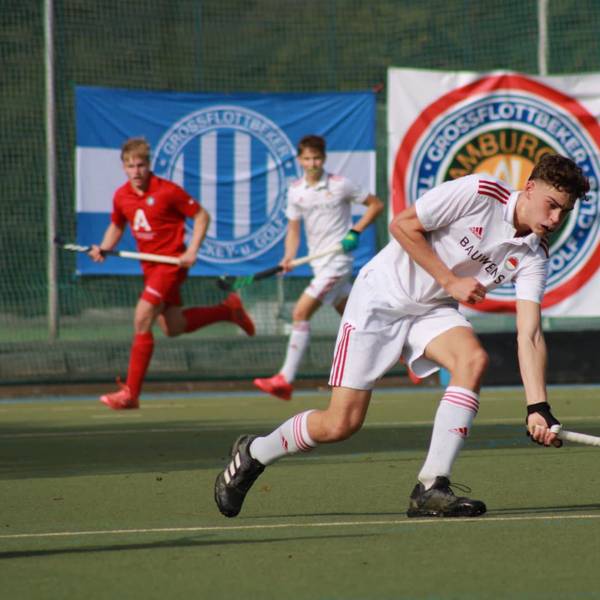 Ein Hockeyspieler läuft über den Platz und stoppt den Ball.