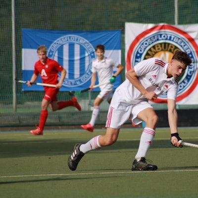 Ein Hockeyspieler läuft über den Platz und stoppt den Ball.