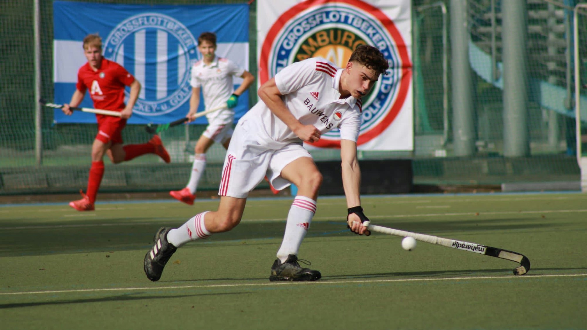 Ein Hockeyspieler läuft über den Platz und stoppt den Ball.
