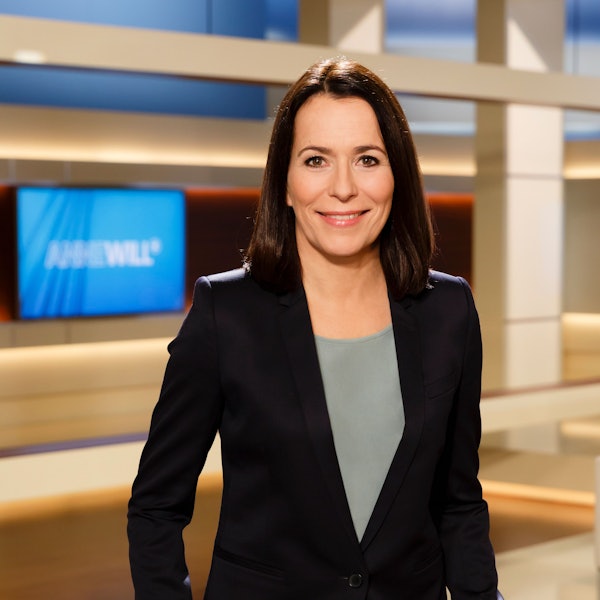 Moderatorin Anne Will steht im Studio vor dem Logo der Sendung „Anne Will“