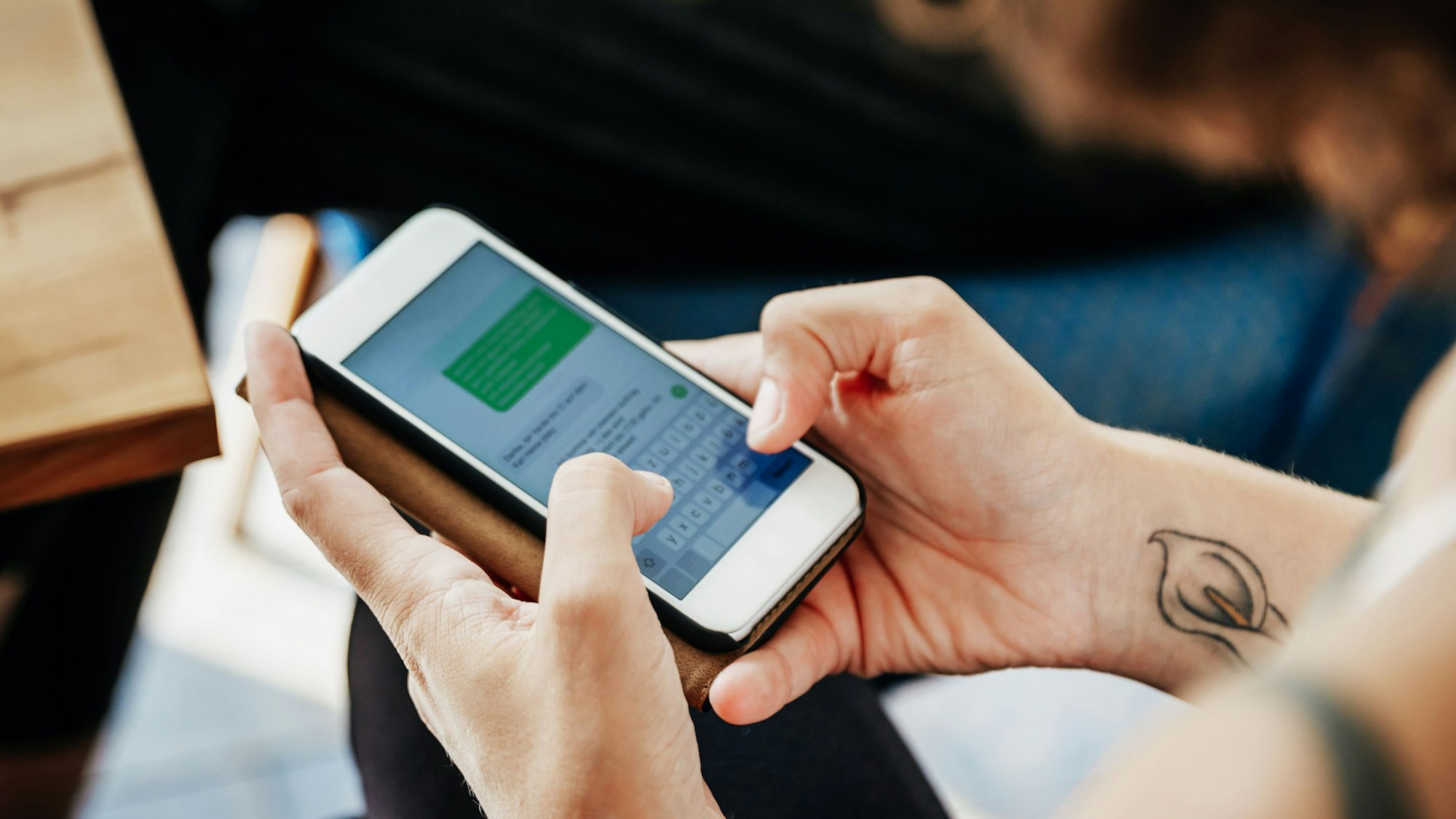 Close-Up einer Frau, die eine SMS versendet.