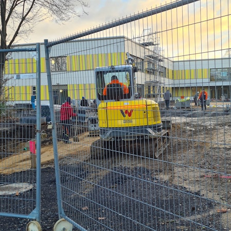 Eine Baustelle zeigt sich hinter dem Bauzaun: Beim Bau der Fortunaschule in Oberaußem wurde beim Anbringen der Fassade gepfuscht.