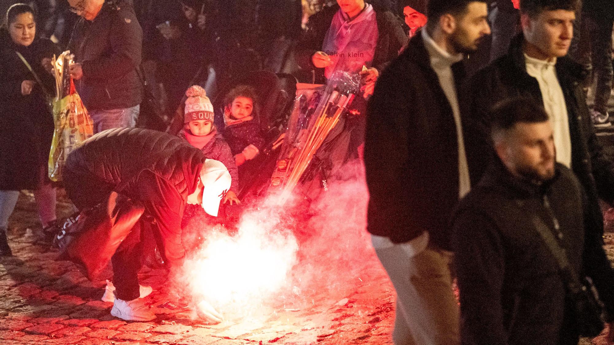Ein Mann zündet am Silvesterabend 2022 eine Rakete mitten in einer Menschenmenge im Rheingarten in der Kölner Innenstadt