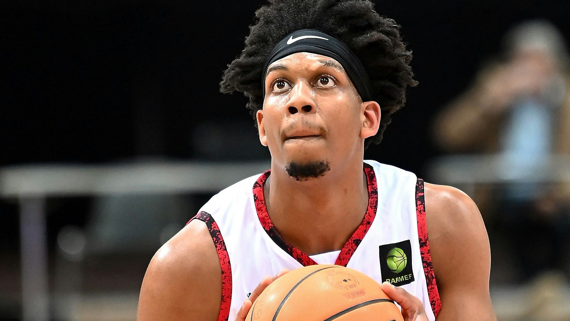 Ein Basketballer richtet vor einem Freiwurf den Blick auf den Korb.