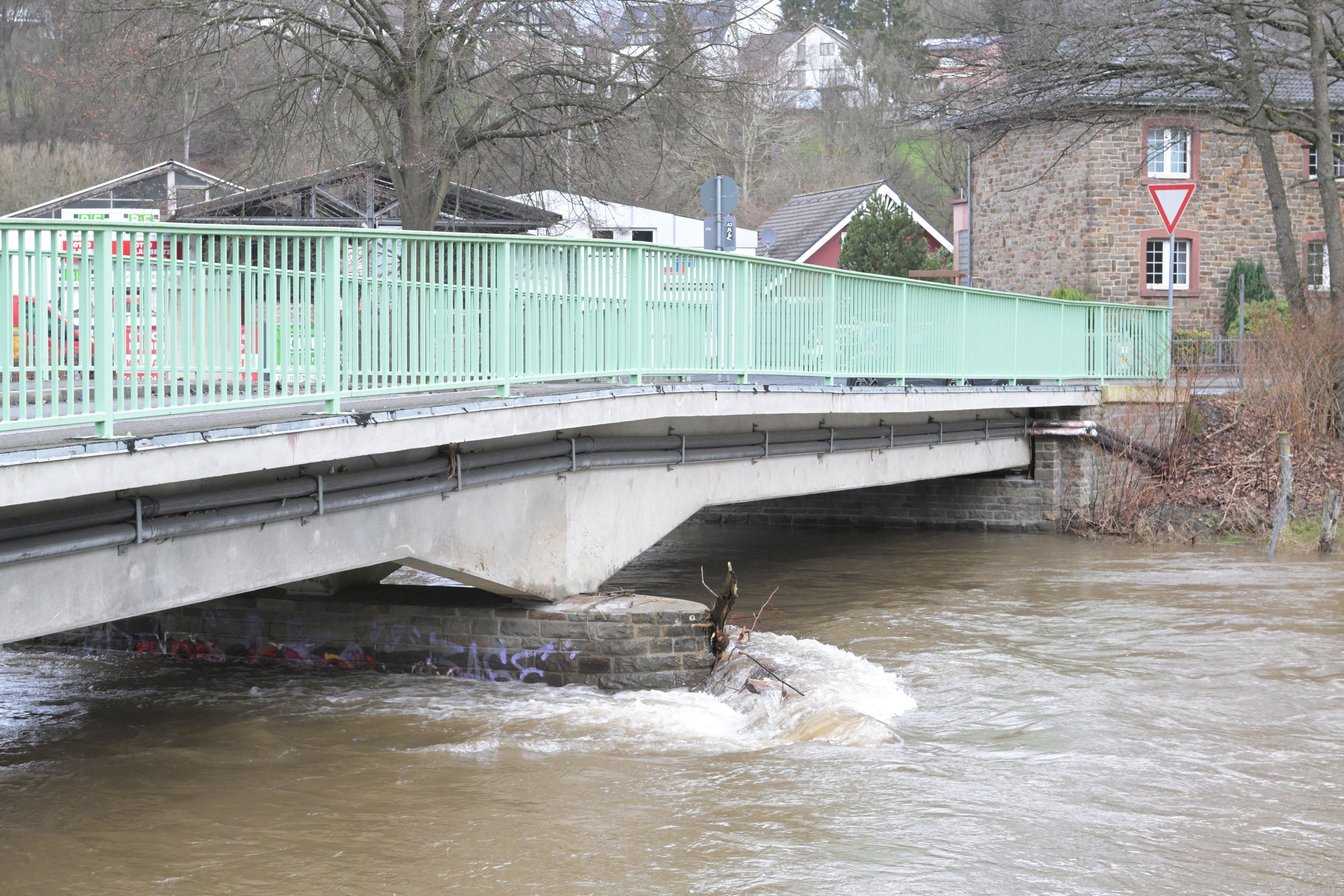 Hochwasser fließt unter einer Brücke hindurch.